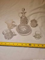 All six pressed glass items arranged with tape measure for scale