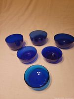 Six cobalt blue glass finger bowls arranged on surface