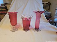 Three cranberry glass vases grouped for overview