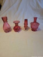 Front view of all four cranberry glass vases