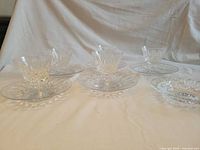 Five crystal dessert cups on saucers displayed on table