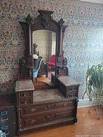 Front view of mirror dresser showing carved walnut frame, marble-topped pedestals and drawers