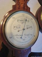 Close-up of marquetry barometer dial showing scale and inscriptions