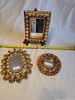 Front view showing all three gilded mirrors with measuring tape for scale