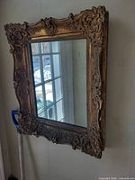 Full view of gilt framed mirror hanging on wall