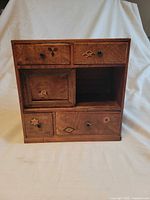 Front view showing all drawers, door, open compartment, inlay designs