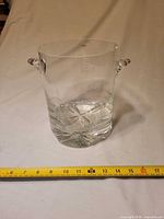 Front view of clear glass ice bucket with ruler showing height
