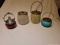 group shot of four colored glass lidded pots