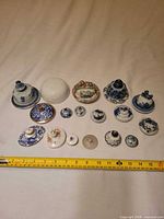 Group view of 17 assorted ceramic lids with measuring tape