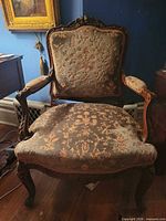 Front view of armchair showing upholstery and carved frame