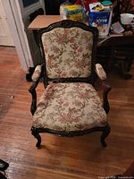 Front view of carved wood armchair with bird and tree patterned upholstery