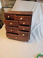 Front view showing 8 drawers with bone knobs and marquetry patterns