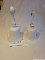 Two milk glass bells and cracker utensil displayed on fabric backdrop