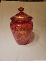 Front view of cranberry glass jar with lid
