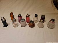 Front view of 11 assorted glass shakers lined up