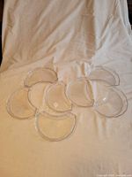 Seven clear crescent dishes arranged on cloth