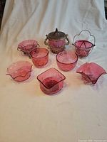 Group view of all nine cranberry glass candy dishes with three metal stands