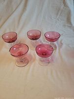 All five cranberry coupe glasses upright on surface