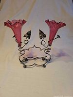 Front view showing both cranberry glass vases in metal stand