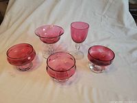 All five cranberry glass pieces grouped