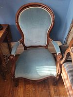 Front view of Victorian chair showing blue velveteen upholstery and carved wood frame