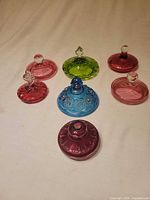 All seven glass lids arranged showing colours and finials