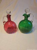 Both cranberry and green glass decanters side by side