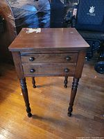 Front view showing two drawers, turned legs, knobs