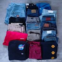 Stack of 18 folded jeans and pants in assorted colors and fabrics