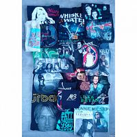 All 20 folded tees arranged; identifiable artist graphics visible