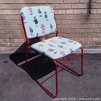Full view of chair showing upholstery pattern and red metal frame