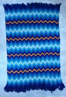 Full view of afghan laid flat showing complete chevron pattern and fringe