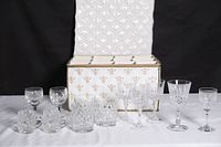 All 12 crystal glasses displayed in front of open padded storage chest