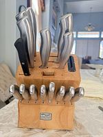 Front view of knife block showing Chicago Cutlery logo, block, 8 steak knives, 6 larger stainless knives, 2 black-handle knives