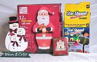 Overall lot showing boxed inflatable Santa, Star Shower Motion box, Lenox ornament box and snowman sign