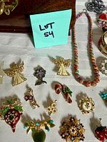 Assorted brooches and bead necklace with Lot 54 note visible