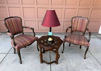Full set showing both striped armchairs, round side table, and burgundy-shade lamp