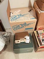 Sony Topcorder recorder sitting on green case beside boxes