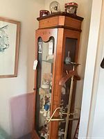 Tall wooden display cabinet holding numerous figurines; snow globes and carousel on top