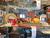 Full shelf view showing clock, mugs, diorama, coasters, plush bear and other decor items