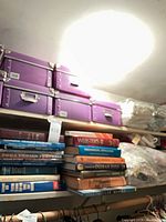 Overall view of purple storage boxes, stacked hardcover books, bagged quilts