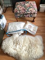 Ottoman, sheepskin rug and both packaged bedding sets together
