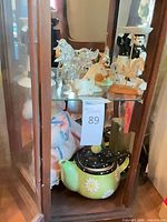 View of shelf with teapot, porcelain horses, glass horses and other figurines