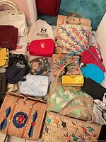 Overview of assorted straw totes, coloured bags, wallets, pouches and accessories spread on floor