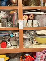 Cabinet shelves showing mugs, owl cups, plastic cups, pitcher and glassware