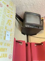 Front angled view of small black CRT TV with VCR mounted on black wall bracket