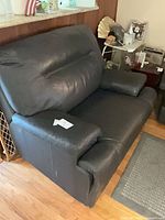 Front angle of black leather loveseat showing seating area and arm cushions