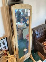 Full view of cheval mirror standing near couch