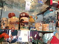 Shelf view showing Coors steins, USC football, mugs, globe bowl and toy car
