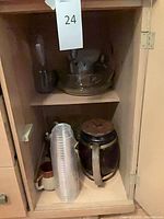 Cabinet view showing cookie jar, clear cups, mug, glass bowls and carafe